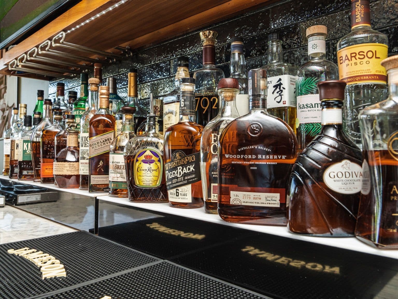 The back bar: a lit shelf lined with bourbon, whiskey and tequila bottles.