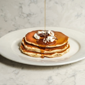 syrup dripping onto pancakes with butter